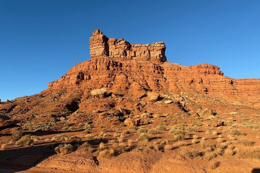 A rugged red rock formation with sparse vegetation. 5