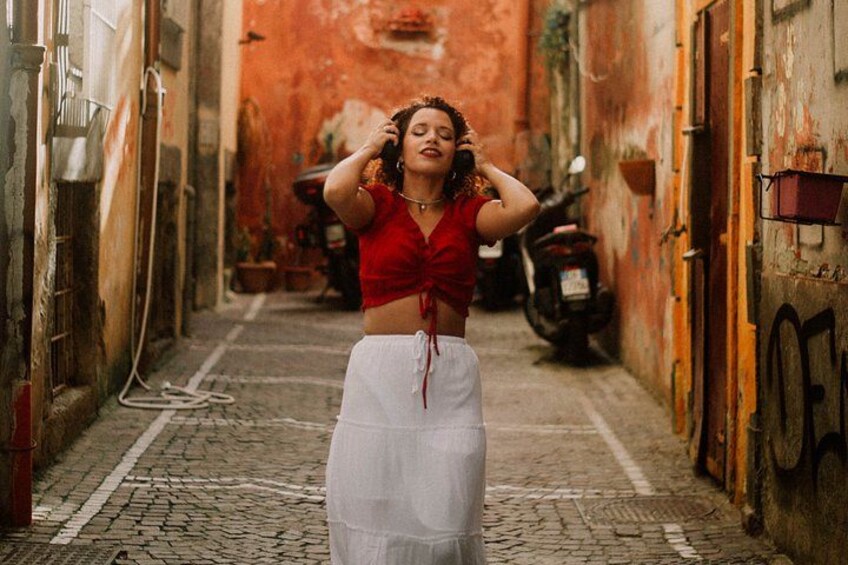A narrow alleyway with cobblestone pavement, a red wall, and a parked motorcycle. 1
