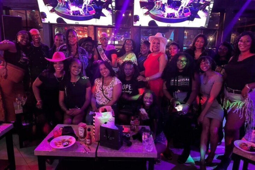 A group of people at a social event with a stage and screens in the background. 2