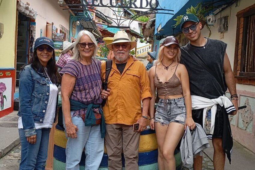 A group of people standing on a colorful street with buildings and a sign that reads 'ECUADOR'. 1