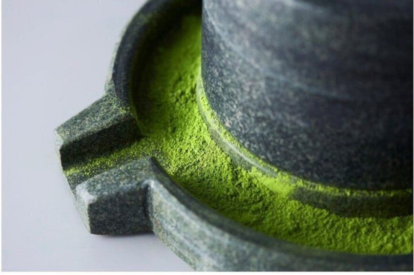 A close-up of a grinding mechanism with a green powder residue. 1