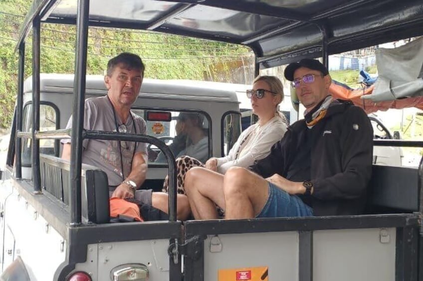 Three people seated inside a vehicle with a roof, a steering wheel, and a rearview mirror. 4