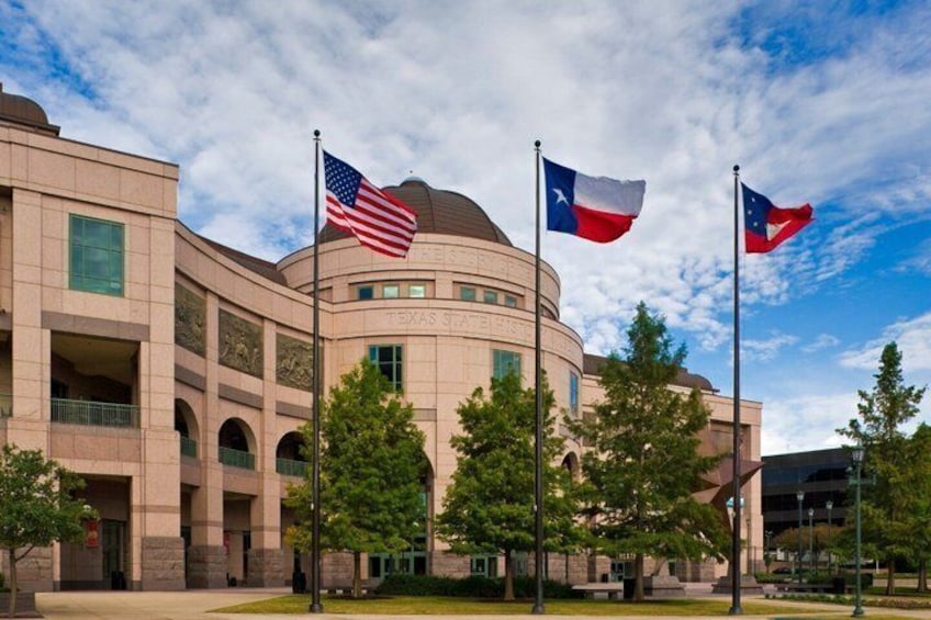 A building with the Texas State Capitol flag, the Texas flag, and the American flag. 3