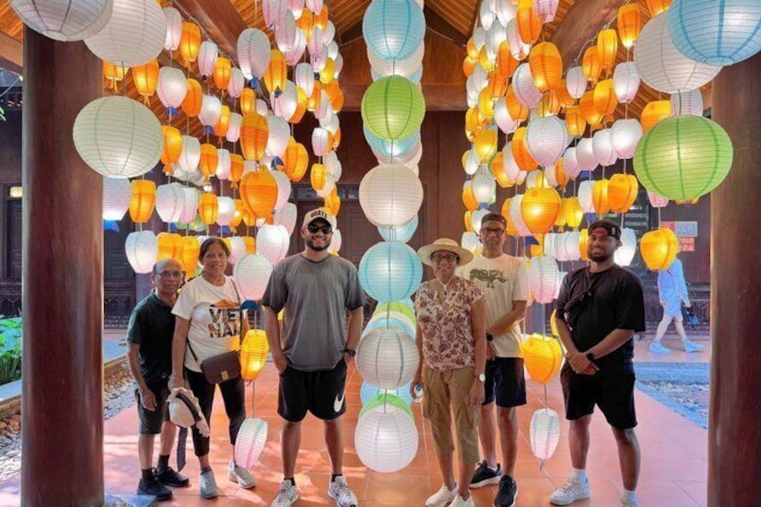 A group of people standing under a canopy of hanging paper lanterns. 3
