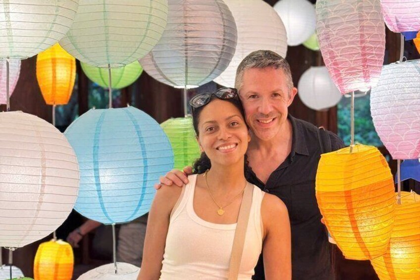 A couple standing under colorful paper lanterns. 2