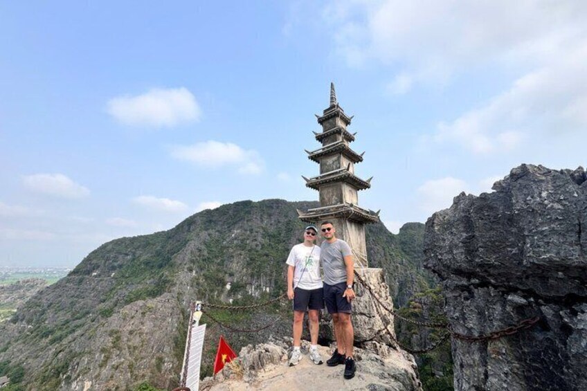 Two people standing on a rocky outcrop with a pagoda in the background. 4