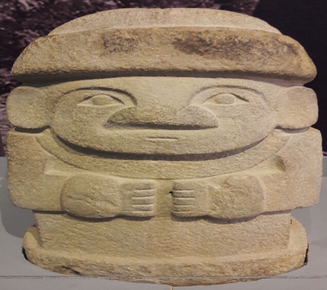 A stone sculpture with a carved face, a hat, and a bow tie. 2