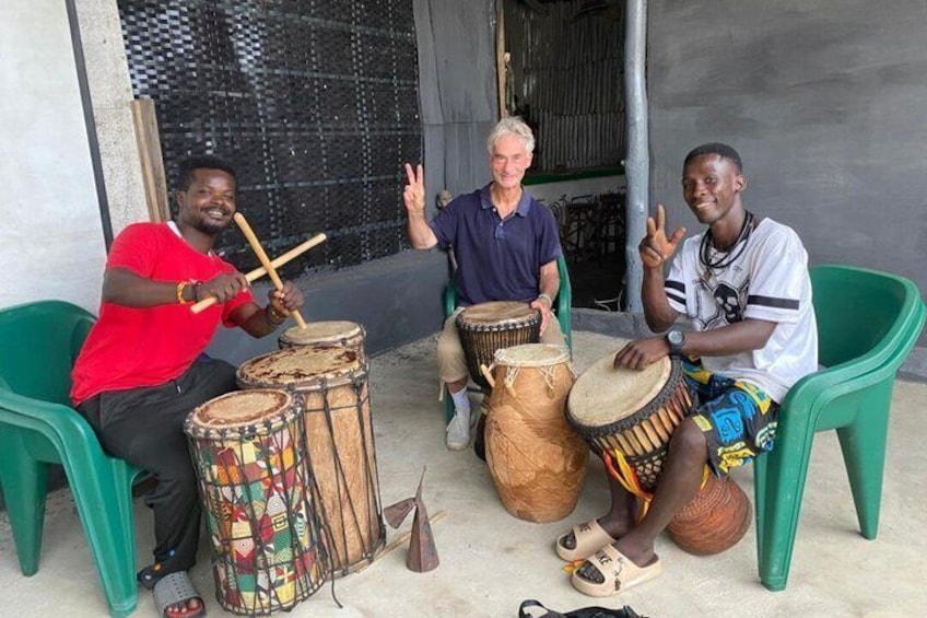Three people seated on green chairs playing drums. 3