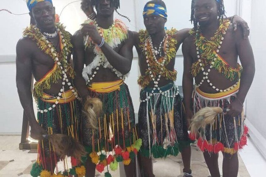 Four individuals in traditional attire with beaded necklaces and feather decorations. 5