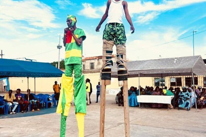 Two individuals performing an acrobatic act on elevated wooden platforms in an outdoor setting with an audience. 4