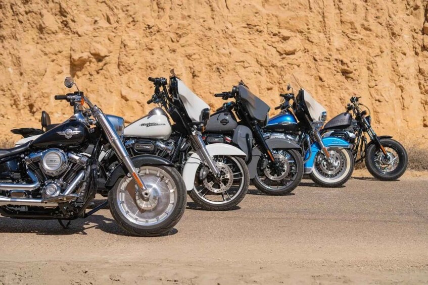 A row of motorcycles parked against a sandy cliff. 5