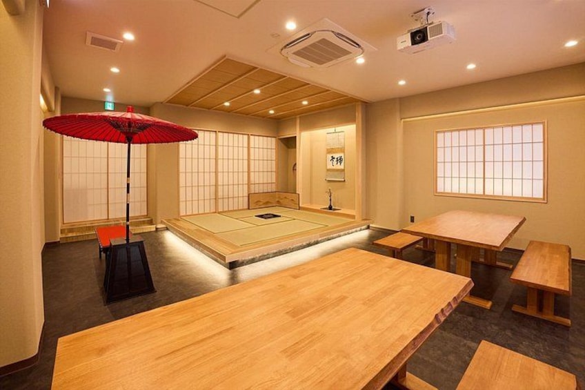 A traditional Japanese room with tatami flooring, a tatami mat table, a red umbrella, and a projector. 2