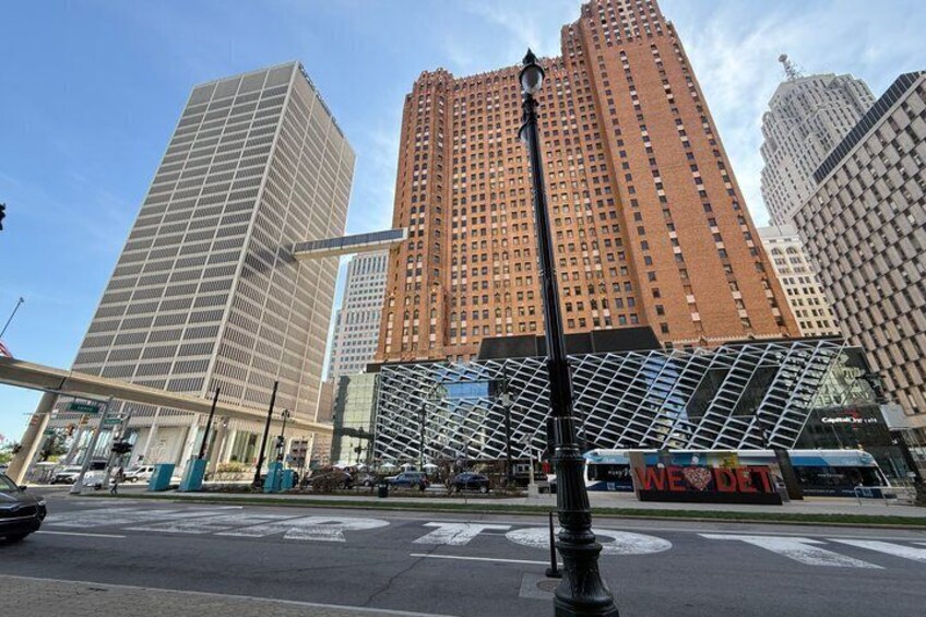 A cityscape with modern high-rise buildings, a street with a bus, and a prominent sign with 'WE LOVE DET' on it. 2