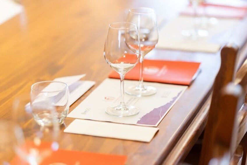 A dining table with wine glasses and orange placemats. 4
