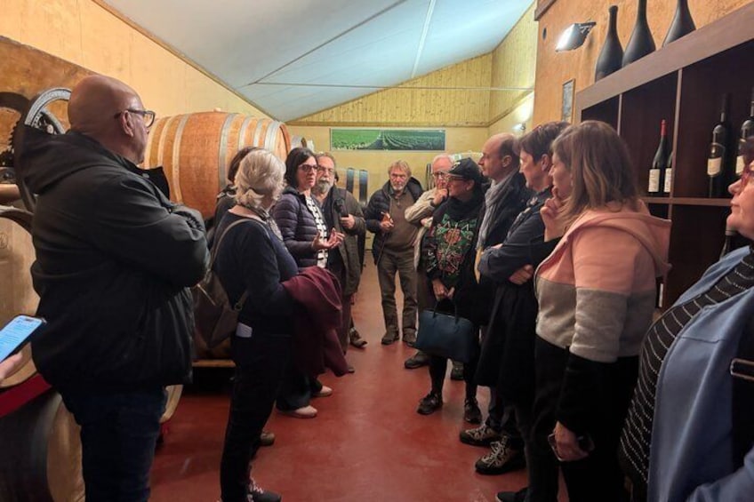 A group of people inside a wine cellar with barrels and wine bottles. 2