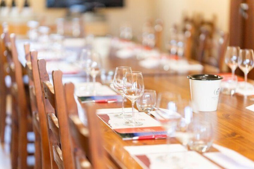 A long wooden table set for a meal with wine glasses and a pitcher. 5