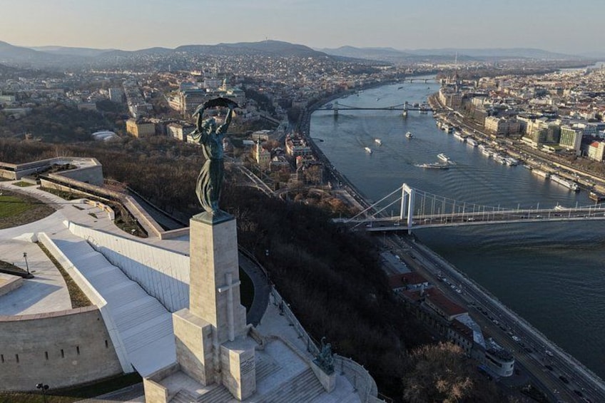 A statue, a river, a bridge, and a cityscape. 4