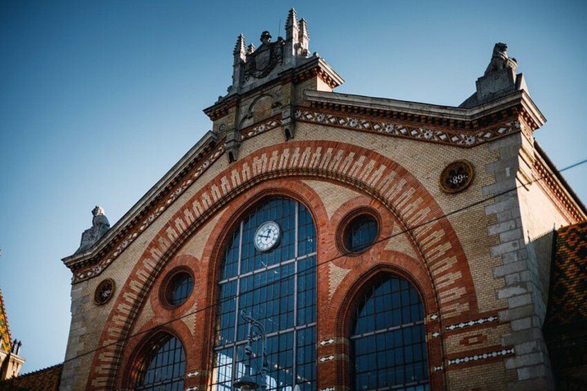 A historic building with a large arched window, a clock, and decorative brickwork. 3