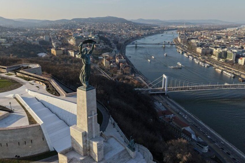 A statue, a river, a bridge, and a cityscape. 3