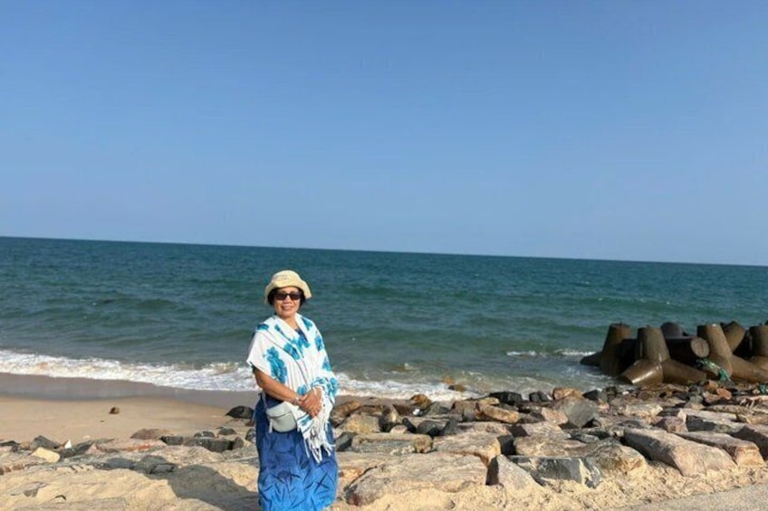 A person standing on a rocky beach with the ocean in the background. 3