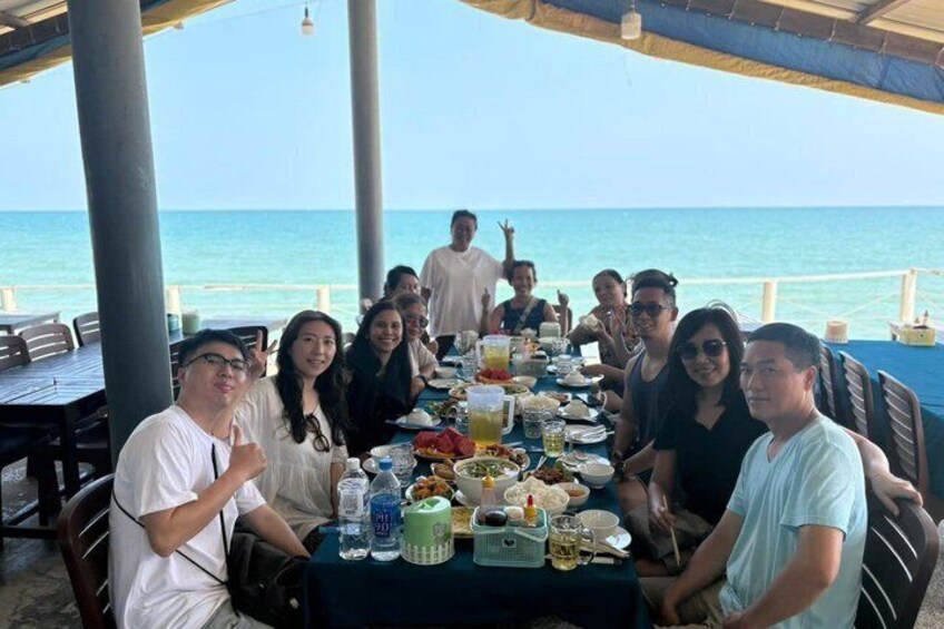 A group of people dining at a table with a view of the ocean. 4