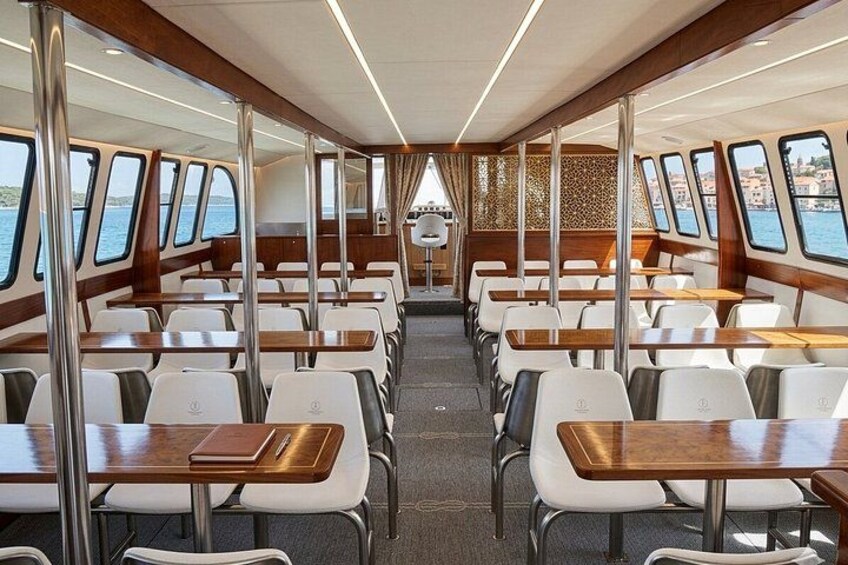 A cruise ship dining area with rows of tables and chairs, large windows, and a view of the sea. 3