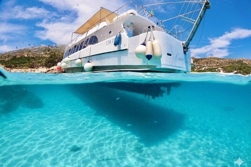 A white boat with a canopy, anchored near a beach with clear turquoise water. 3