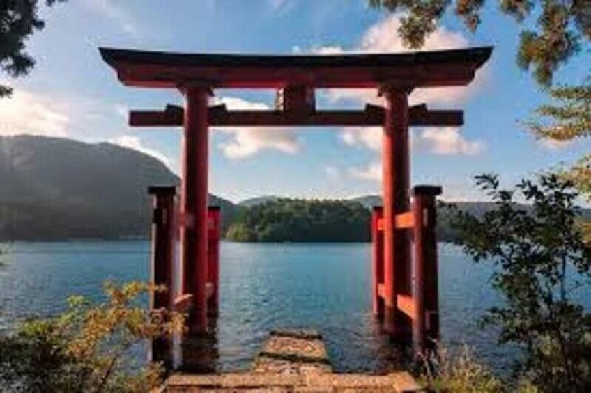 A red torii gate at the water's edge with a clear sky and mountains in the background. 2