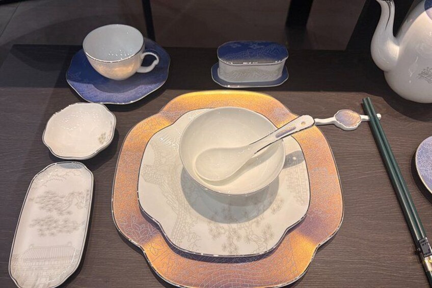 A table with various ceramic dishes, including a bowl with a spoon, a teapot, and several small bowls and plates. 5