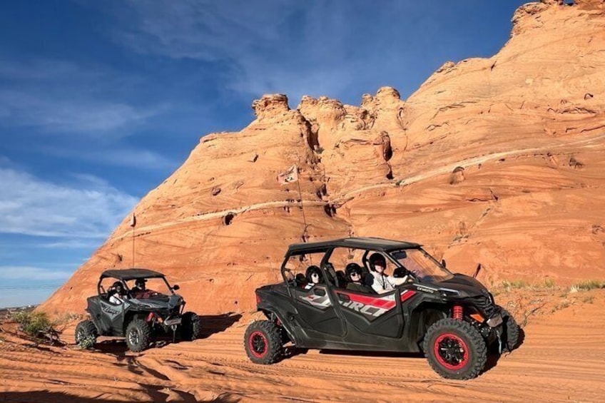 Two off-road vehicles on a desert trail with red rock formations in the background. 5