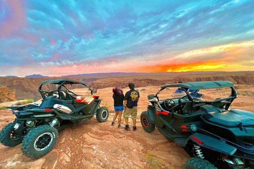 Two off-road vehicles parked on a rocky terrain with a sunset in the background. 3