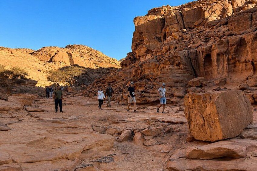 A rocky desert landscape with large boulders and a group of people hiking. 3