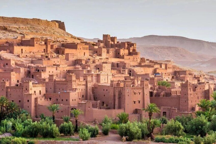 A traditional mud-brick village with fortified structures and palm trees. 4