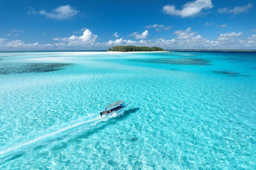 A boat on turquoise water with a clear sky and a distant island. 4
