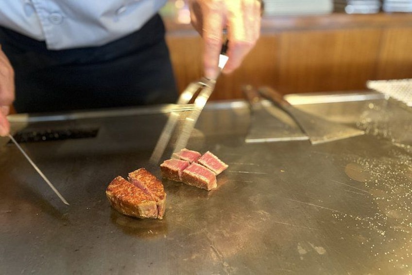 A person slicing meat on a hot griddle. 3