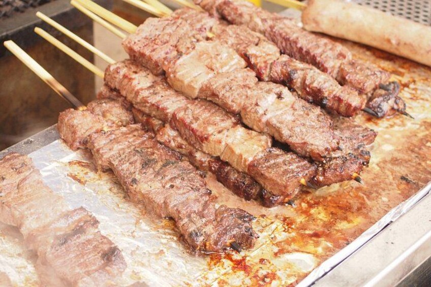 Skewered meat grilling on a metal surface. 5