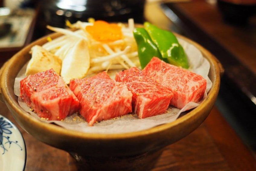 A bowl of sliced meat with vegetables and a yellow item, possibly a fruit. 4