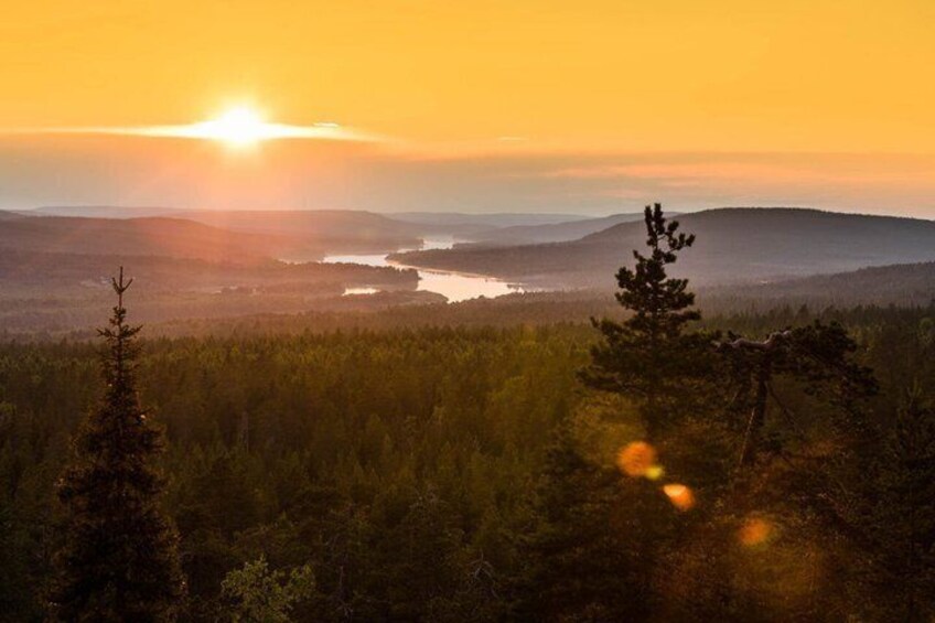 A sunrise over a forested landscape with a river and distant hills. 5