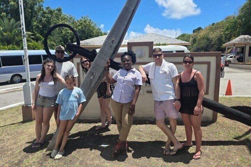 A group of people standing in front of a large wooden structure with a circular object on top. 1