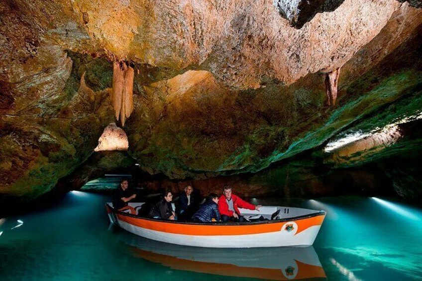 A boat with people inside, surrounded by cave walls and water. 4