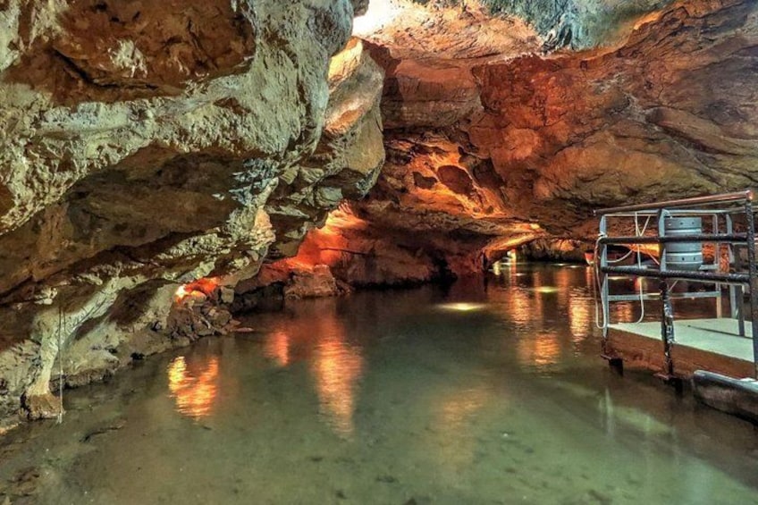 A cave with water reflecting light, rocky walls, and a metal structure. 4