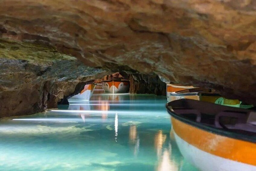 A cave with clear water and boats. 5