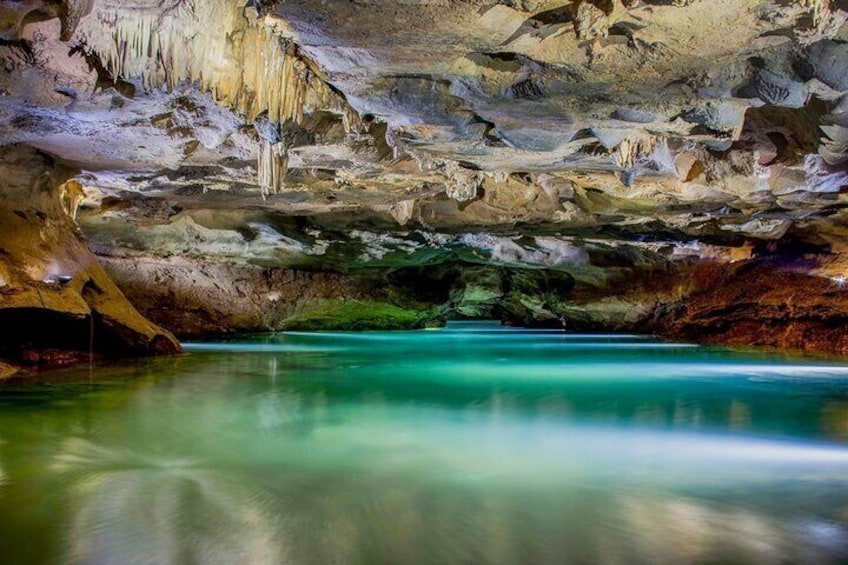 A cave with stalactites and a turquoise pool. 2
