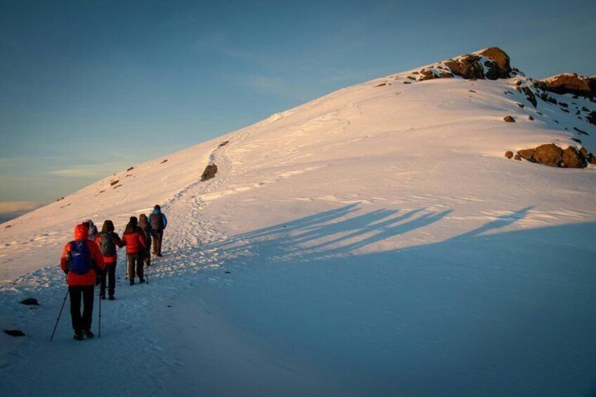 A group of people hiking on a snow-covered mountain trail. 2