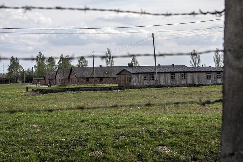 A barbed wire fence, a grassy field, and a row of wooden buildings. 4