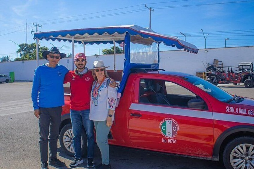 A red and white utility vehicle with a canopy, parked in a lot with a clear sky. 1