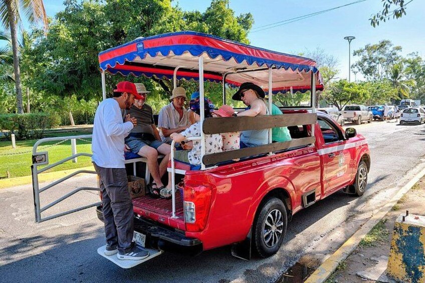 A red pickup truck with a canopy, parked on a street with people around it. 4