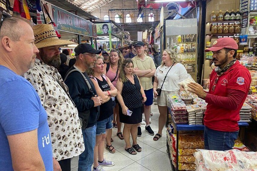 A group of people in a market with various food items on display. 5