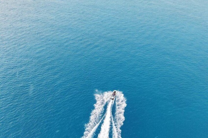 A boat creating a wake in a vast blue sea. 5