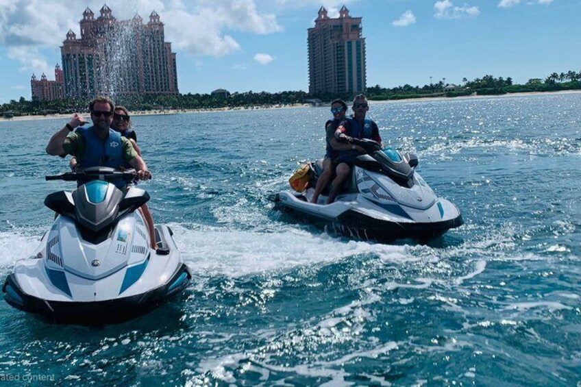 Two jet skis on a body of water with a large resort building in the background. 4